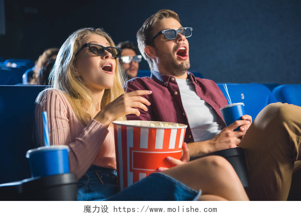 在电影院内看电影的两个人震惊的情侣在3d 眼镜与爆米花一起看电影在电影院